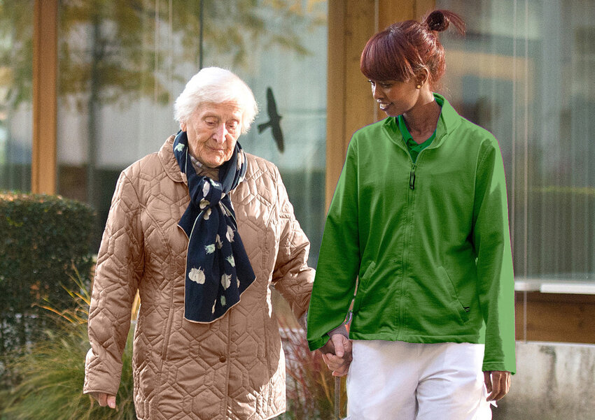 Alte Frau spaziert mit Pflegerin Hand in Hand